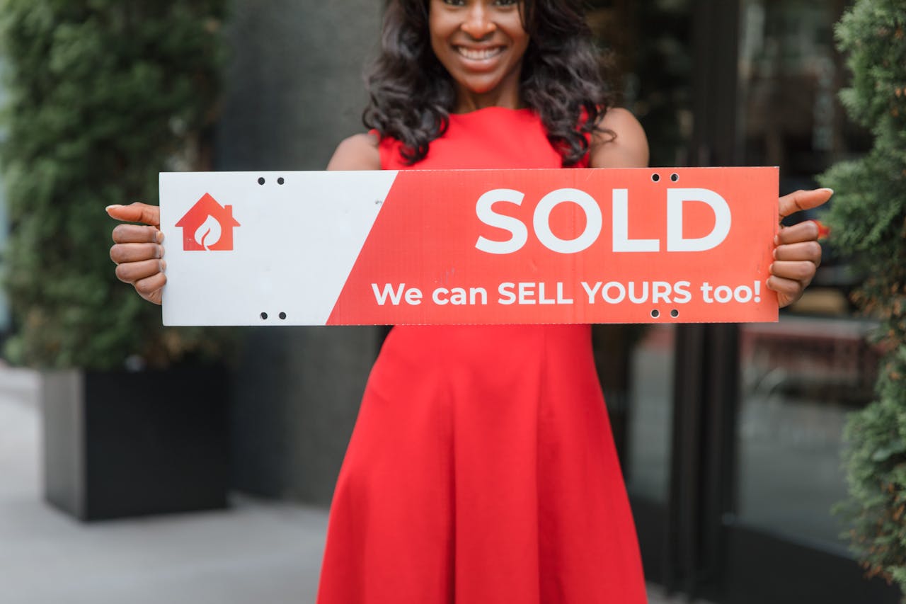 services-01 Smiling woman holding a 'Sold' sign, symbolizing successful real estate sales.
