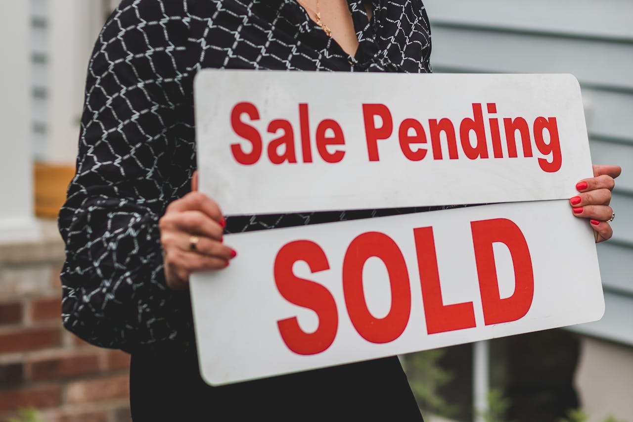 services-04 A businesswoman holding 'Sale Pending' and 'Sold' signs indicating a successful real estate transaction.