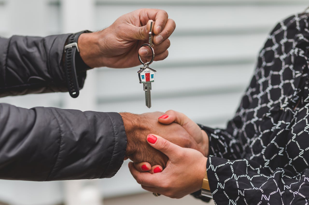 about-01 Close-up of a realtor handing over a house key to a new homeowner, symbolizing ownership and investment.