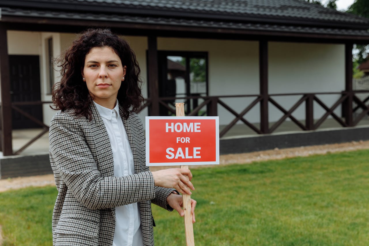 services-03 Confident real estate agent with sale sign in front of a house.