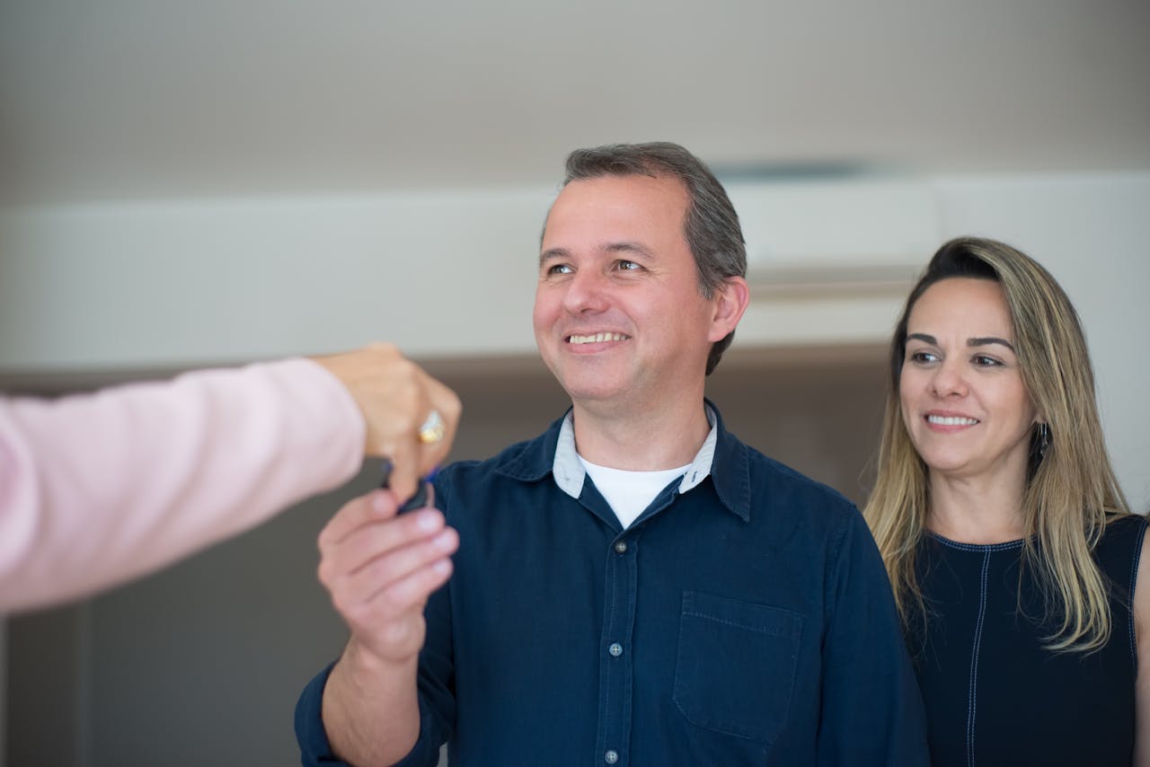 about-img Smiling couple receiving keys, celebrating new home purchase indoors.